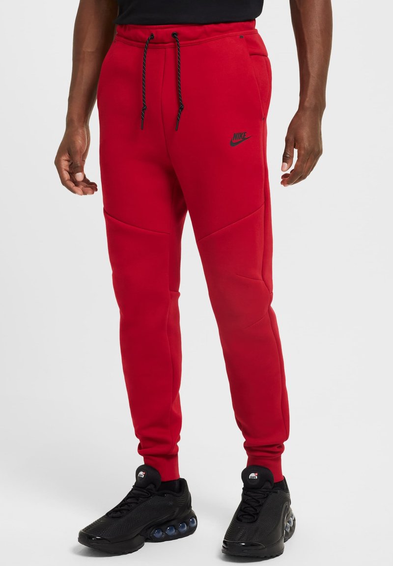 Pantalons de survêtement rouges avec taille élastique, cordon de serrage ajustable, logo Nike noir et poches. Conçus avec une coupe fuselée et une texture lisse.