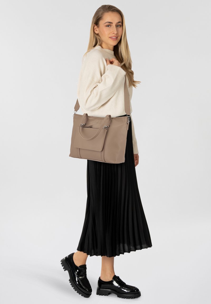 Beige leren handtas met dubbele handgrepen en een afneembare schouderriem. Bevat een ritssluiting zak en een vlakke voorpaneel.