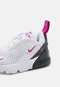 Valge võrkmaterjalist sneaker roosa ja musta aktsentidega, millel on tekstureeritud pind, pehmendatud põhi ja tõmbeosa kanna juures.