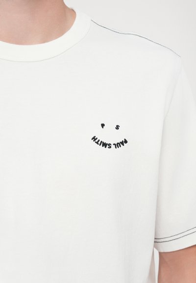 White cotton t-shirt featuring a small black embroidered smiley face design with "PS Paul Smith" text in a curved layout above it.