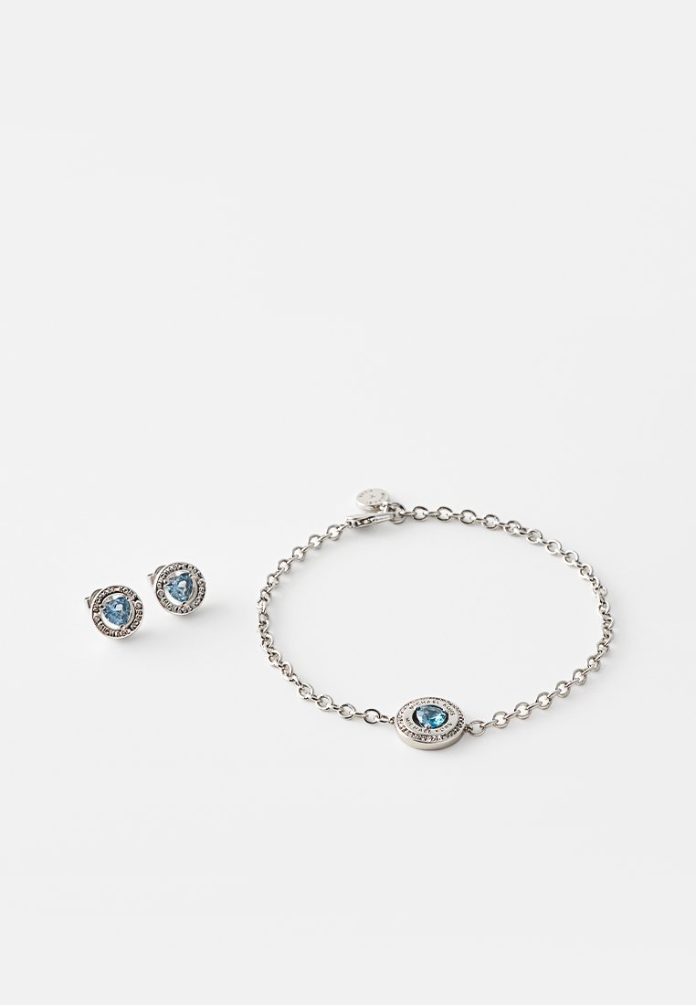 Srebrny zestaw biżuterii z kolczykami na sztyfcie i bransoletką. Każdy element ma niebieski kamień szlachetny otoczony teksturowaną, okrągłą oprawą.