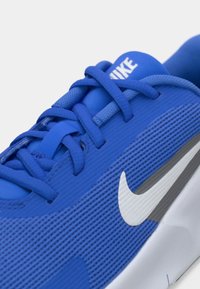 Μπλε αθλητικό παπούτσι με υφασμάτινη επάνω επιφάνεια με υφή, επίπεδα κορδόνια και λευκό λογότυπο Nike. Μαλακή επένδυση και μαξιλαρωμένη σόλα για άνεση.