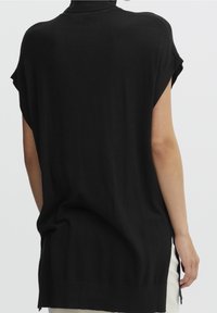 Svart, kortärmad topp med hög krage, har en avslappnad passform, mjuk textur och sprund i fållen för ökad rörelsefrihet.