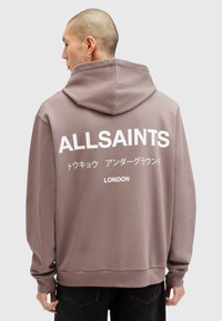 Hættetrøje i dæmpet mauve, med stort hvidt tekst på ryggen med "ALLSAINTS," japanske tegn og "LONDON." Blødt stof, afslappet pasform.