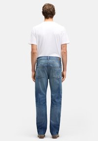 Niebieskie dżinsy z prostą nogawką, pięcioma kieszeniami i klasycznym, wyblakłym wykończeniem. Połączone z gładkim białym t-shirtem.