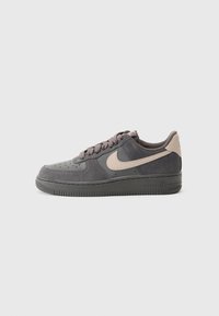 Nike Air Force 1 sneakers i mörkgrå mocka med beige accenter, rundad tå, texturerad sula och platta skosnören. Synliga perforeringar på tåboxen.