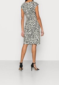Hame fluviile cap-sleeves, în culoare off-white, cu imprimeu cu buline negre, siluetă ajustată, lungime până la genunchi și închidere cu fermoar la spate. Purtați cu tocuri negre.
