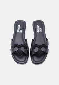 Μαύρα σανδάλια Moschino slide με λουράκια σε σχήμα καρδιάς διακοσμημένα με μικρές μαύρες χάντρες, τετράγωνη μύτη, επίπεδη σόλα.
