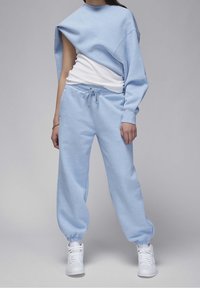 Sudadera azul claro con un diseño asimétrico y una manga larga, combinada con joggers azules a juego que cuentan con cintura y puños elásticos.