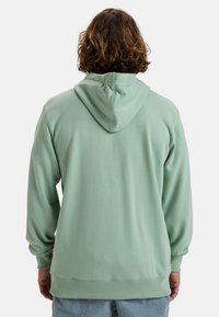Mint green hoodie with a kangaroo pocket, featuring a drawstring hood and ribbed cuffs. Made from soft, textured fabric.