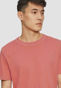 Korte mouwen, ronde hals t-shirt in licht koraal, gemaakt van zachte katoen, met een gladde textuur en eenvoudig ontwerp, met minimale naden.