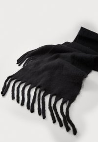 Écharpe en laine noire présentant une texture douce, avec des bords frangés et une forme rectangulaire, posée à plat sur un fond clair.
