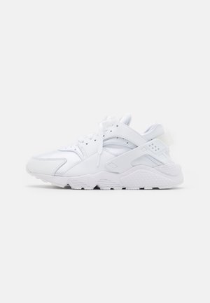 Scarpa da ginnastica bianca con dettagli in mesh e materiali sintetici, chiusura con lacci e suola spessa e strutturata, vista di profilo su sfondo semplice.
