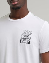 Uomo che indossa una maglietta bianca con un disegno a linea nera di una scatola di pastelli Crayola e la scritta "Lee" stampata sul petto.