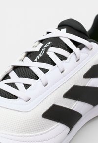 Scarpa sportiva bianca con dettagli neri, realizzata in materiali mesh e sintetici, con lacci piatti e un audace marchio "Predator" sulla linguetta.