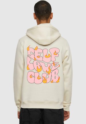 Cremefarbene Kapuzenjacke mit pinkem Aufdruck "SELF LOVE CLUB" und Flammenakzenten. Hergestellt aus einem glatten Stoff. Mit Kängurutasche vorne.
