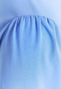 Tissu bleu clair avec des plis froncés créant des plis doux et de la texture en gros plan.