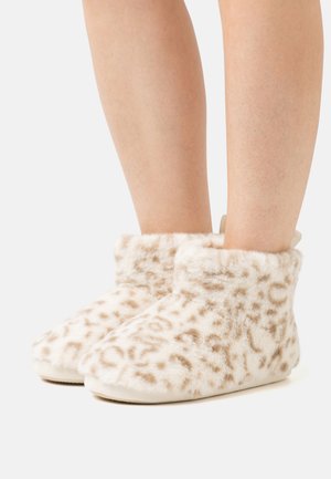 Flauschige beige Hausschuhe mit einem Leopardenmuster, die eine weiche Textur, eine Knöchelhöhe und eine flache, glatte Sohle aufweisen.