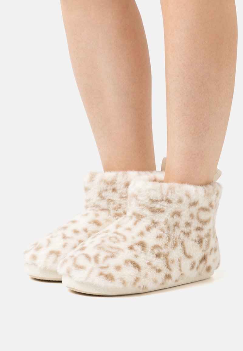 Furry beige slippers with a leopard print pattern, featuring a soft texture, ankle height, and a flat, smooth sole.