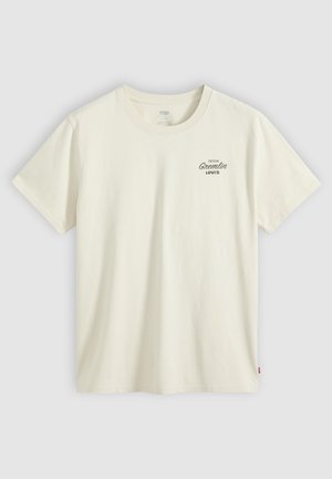 Off-white Levi's T-skjorte med korte ermer og liten svart "Denim Gremlin Levi's"-tekst på øvre venstre bryst.