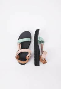 Sandalias multicolores con una suela texturizada negra, correas ajustables en melocotón, marrón y verde menta, diseño plano para mayor comodidad.