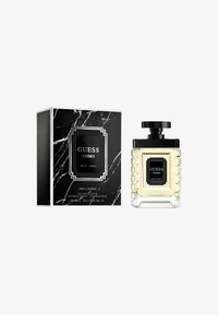 Flacon de parfum Guess Uomo, en verre transparent avec des côtés striés, bouchon noir, entouré d'une boîte à motif marbré noir avec des accents blancs.