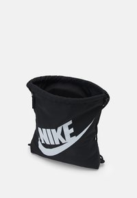 Svart tygdragsäck med en stor vit "Nike"-logotyp. Överdelen är samlad och elastisk för stängning. Lättviktsdesign med en enkel stil.