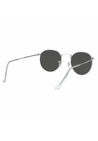 Occhiali da sole rotondi con lenti scure, montatura in metallo argentato, bracci sottili e un design minimalista. Nessun logo o motivo visibile.