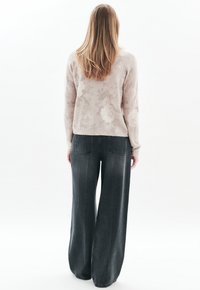 Vaaleanpunainen kukkakuviollinen neule ja leveälahkeiset tummanharmaat farkut, joissa on rento istuvuus ja minimalistinen muotoilu, nähtynä takaa.