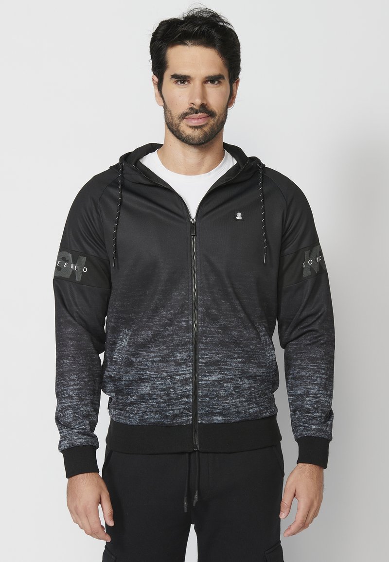 Čierna a šedá zipsová mikina s gradientovým dizajnom, textúrovaná tkanina, kapucňa so šnúrkou a potlačené akcenty na rukávoch.