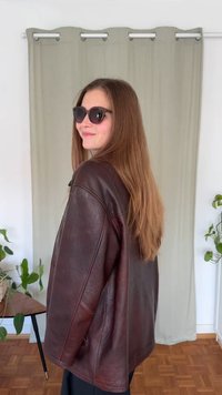 Pruun nahktagi, millel on lõdva istuvus, nähtavad õmblused ja küljetaskud. Kandja kannab musti päikeseprille ja tal on pikad sirged juuksed.