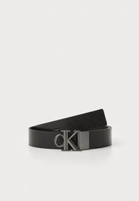 Zwarte leren riem met een gladde textuur en een metallic CK-logo gespsluiting. Het ontwerp heeft een klassieke, minimalistische vorm.