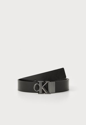 Czarny skórzany pasek o gładkiej fakturze z metalową klamrą z logo CK. Projekt charakteryzuje się klasycznym, minimalistycznym kształtem.