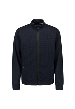 Navy zip-up jack met een gestructureerd voorpaneel, gladde mouwen, staande kraag en een subtiele logo op de borst. Inclusief twee zijzakken.