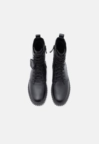 Sorte ankelstøvler i svart skinn med teksturert overflate, rund tå, snøring foran, glidelås på siden og gummisåle med mønstret såle.