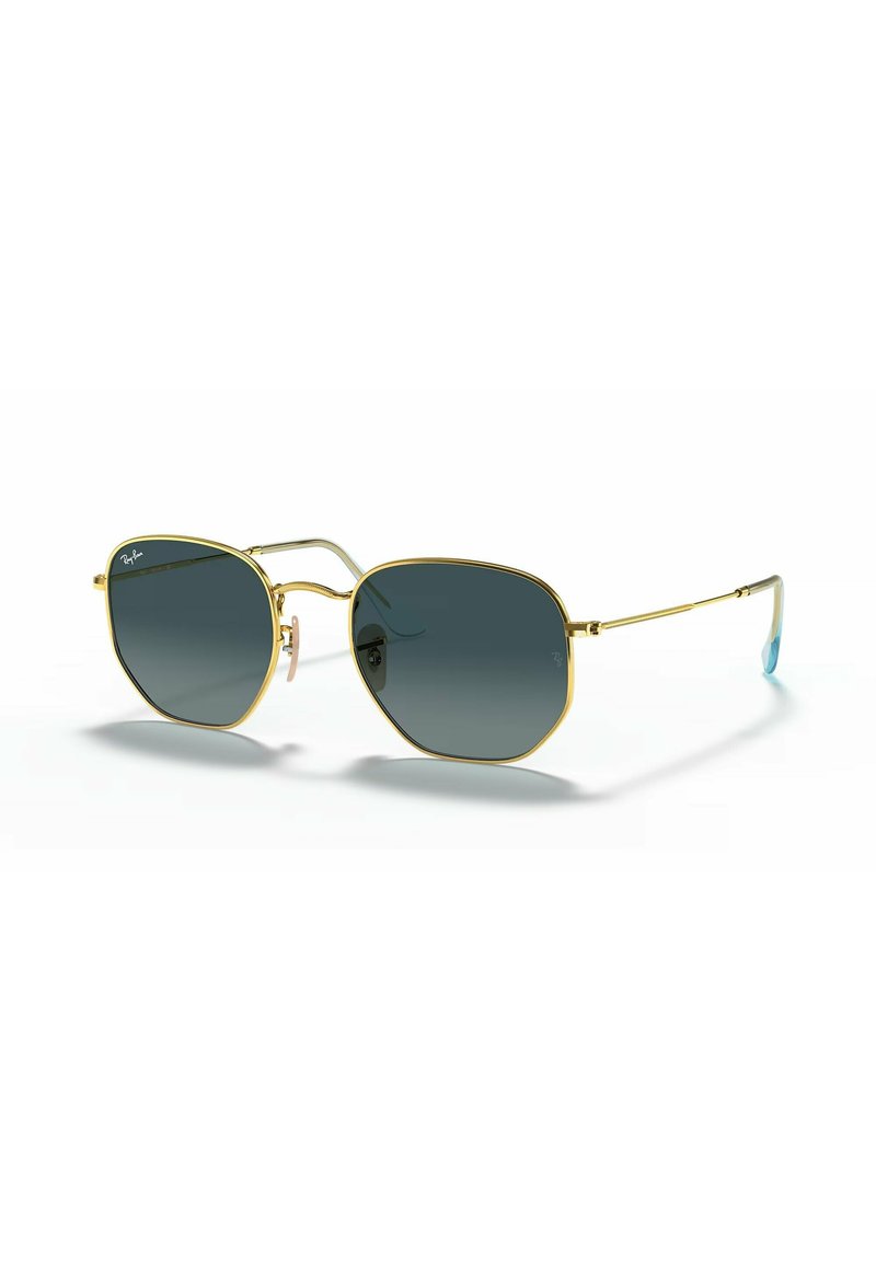 Gafas de sol con montura de metal dorado, forma octagonal, lente oscura con degradado y patillas texturizadas con puntas azules.