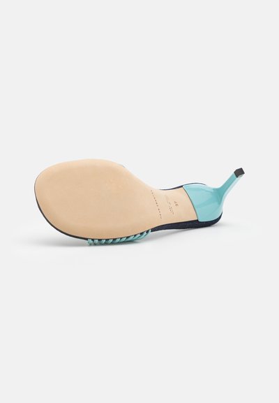 High-heeled shoe with a transparent turquoise upper and black accents, featuring a pointed toe and a textured, beige sole.