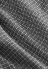 Gray plaid fabric featuring a soft texture with a small checkered pattern, blending lighter and darker shades for subtle contrast.