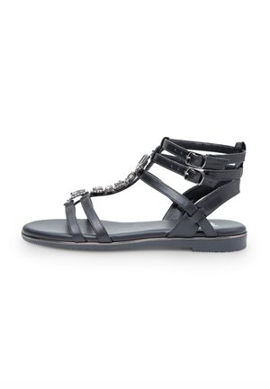 Sandalo in pelle nera con molteplici cinghie e fibbie regolabili. Presenta strass decorativi lungo la parte superiore. Suola piatta.