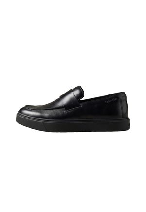 Mocassin noir en cuir à enfiler avec une semelle épaisse en caoutchouc, un bout arrondi et une bride élégante sur le côté supérieur.