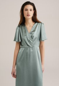 Satin wrap dress in muted green, featuring short flutter sleeves, a V-neckline, and a fitted waist, with a smooth, flowing texture.