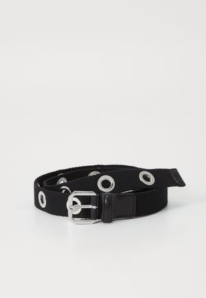 Cinturón de tela negra con ojetes metálicos y una hebilla de metal plateado. Material texturizado con un acento de cuero suave cerca de la hebilla.