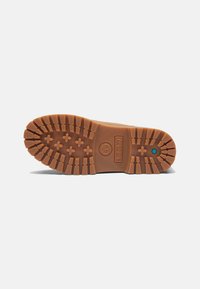 Semelle en caoutchouc avec un motif de crampons brun, dotée de profondes lugs pour une meilleure traction et un accent de logo. Détail hexagonal bleu près du talon.
