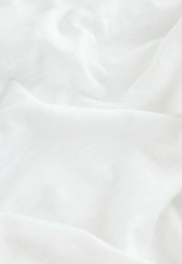 Tissu blanc doux avec des plis subtils, montrant une texture lisse et propre.