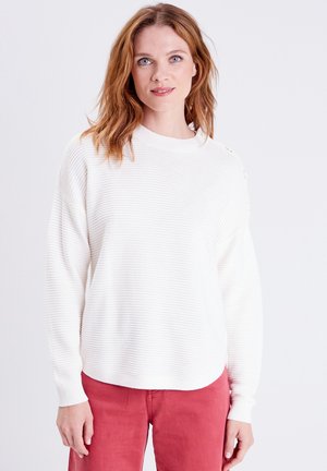 Weißer gerippter Pullover mit Rundhalsausschnitt und langen Ärmeln, ausgestattet mit goldenen Knopfakzenten an der Schulter, kombiniert mit rosa Hosen.