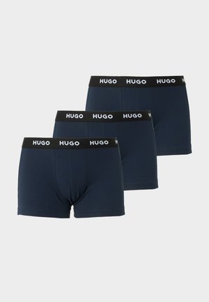 Drei Paare marineblaue Boxershorts mit schwarzen Bundbändern und weißem "HUGO"-Logo, überlappend auf weißem Hintergrund angeordnet.