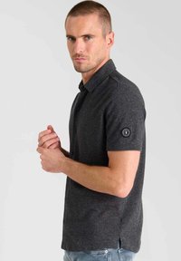 Donkergrijze polo met korte mouwen en een kraag, uitgerust met een logopatch op de mouw, gemaakt van textuurstof met een slim fit.