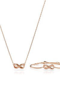 Halskette und Armband aus Roségold mit einem Unendlichkeitssymbol, verziert mit klaren Steinen. Das filigrane Ketten-Design ergänzt das Schmuckstück.