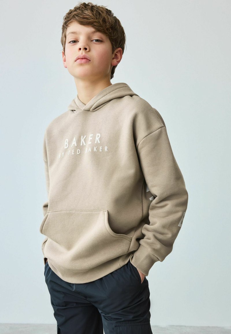 Bež dukserica s prednjim džepom, na kojoj je bijeli natpis "BAKER BY TED BAKER." Ima opušteni kroj i duge rukave.