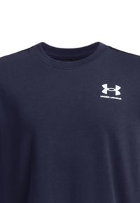 Camisa de manga corta azul marino hecha de algodón, con un cuello redondo y el logo blanco de Under Armour en el pecho. Textura suave.